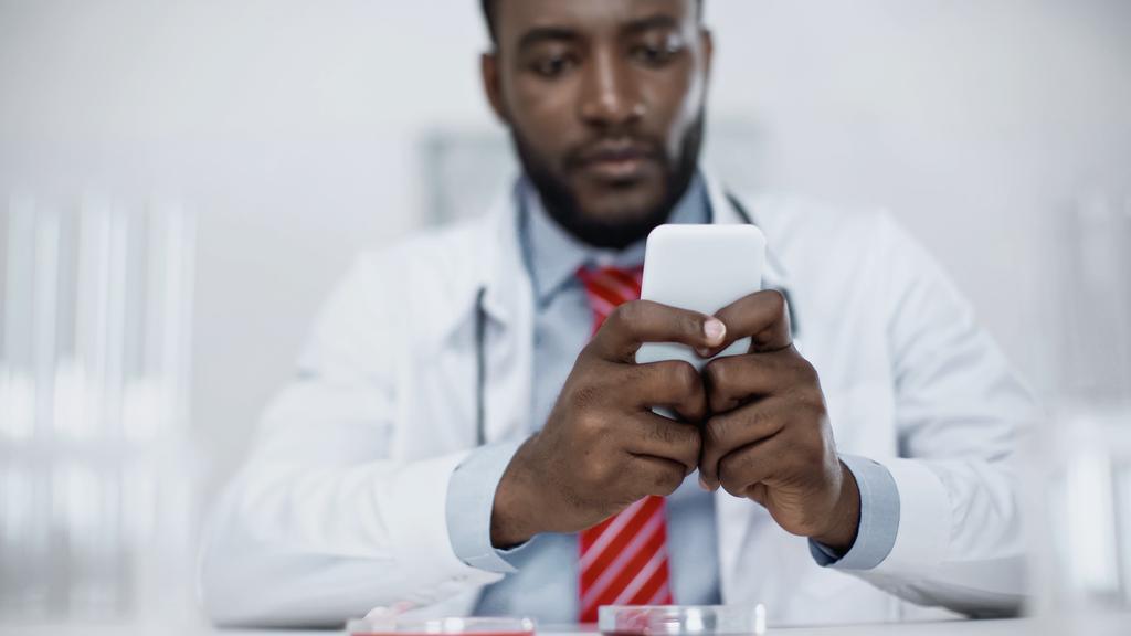 niewyraźne wiadomości od afrykańskiego lekarza na smartfonie  - Zdjęcie, obraz
