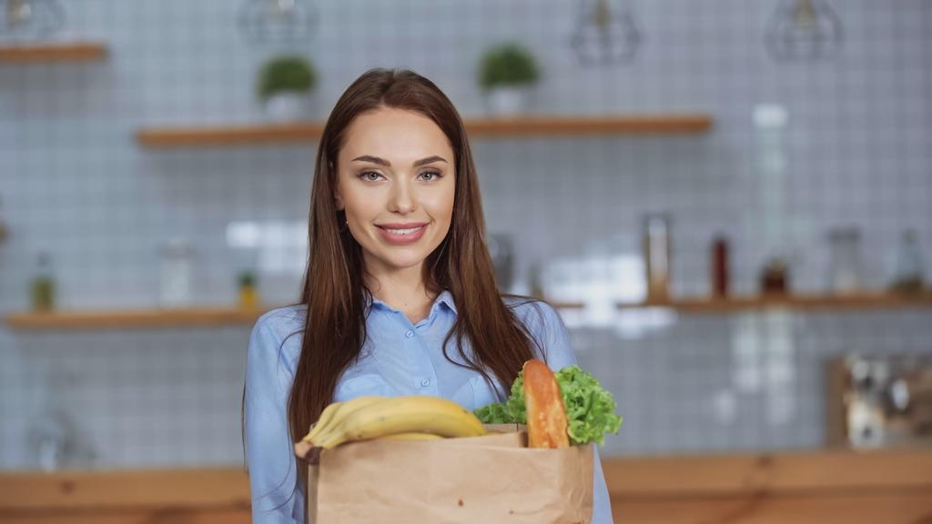 Mosolygó nő kezében csomag élelmiszer otthon  - Fotó, kép