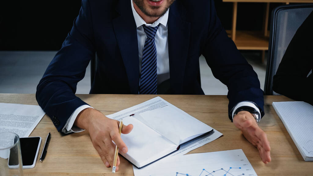 обрізаний вид бізнесмена в формальному носінні жестикуляції біля порожнього блокнота і документів
 - Фото, зображення