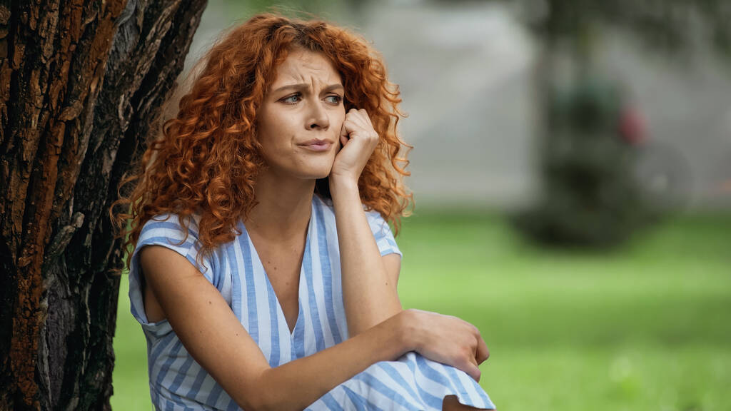 triste giovane donna con i capelli rossi guardando lontano nel parco  - Foto, immagini