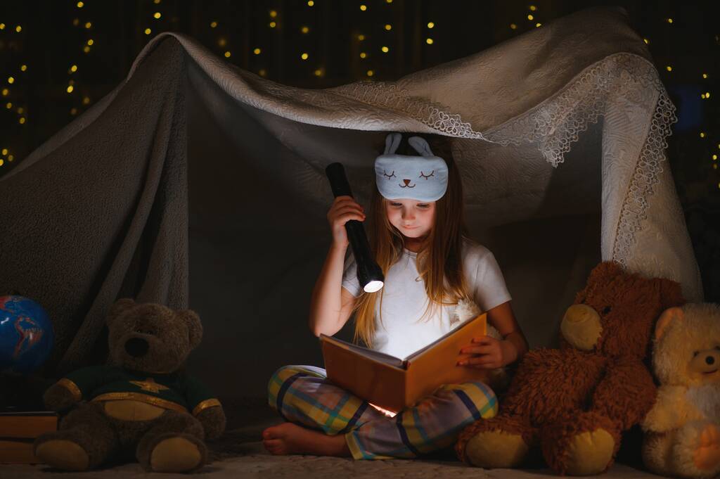Une jolie petite fille lisant un livre sur le sol sous la lampe. Enfants et éducation. - Photo, image