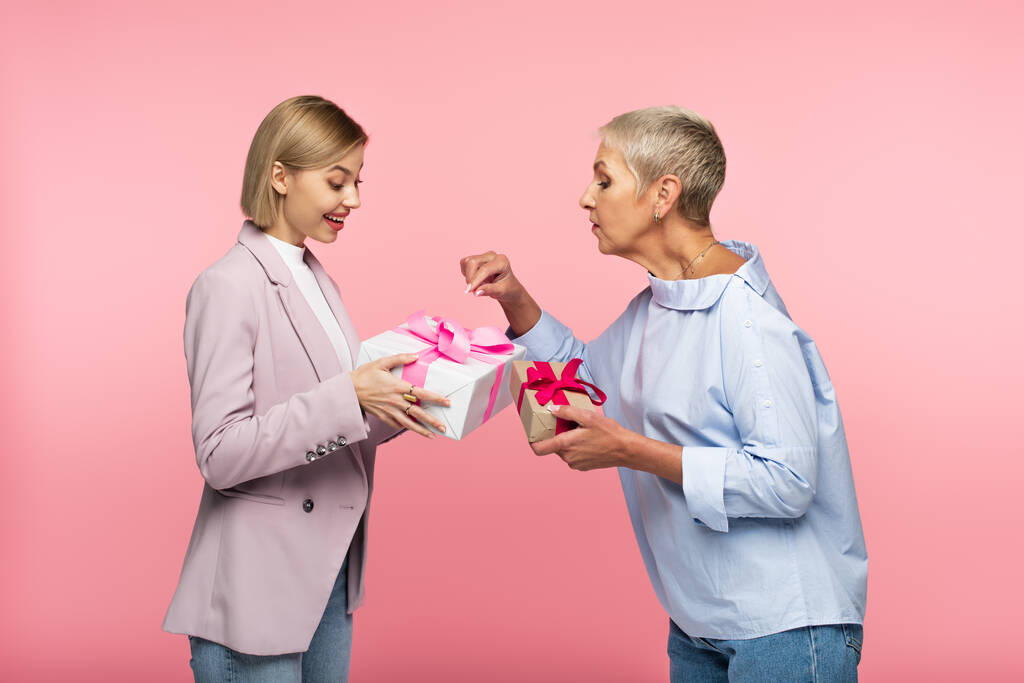 笑顔の若い娘と成熟した母親がピンクで隔絶されたプレゼントを - 写真・画像