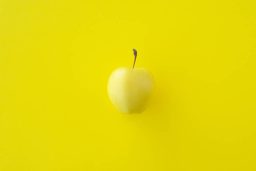 Gele appel op een gele achtergrond, kopieer ruimte - Foto, afbeelding