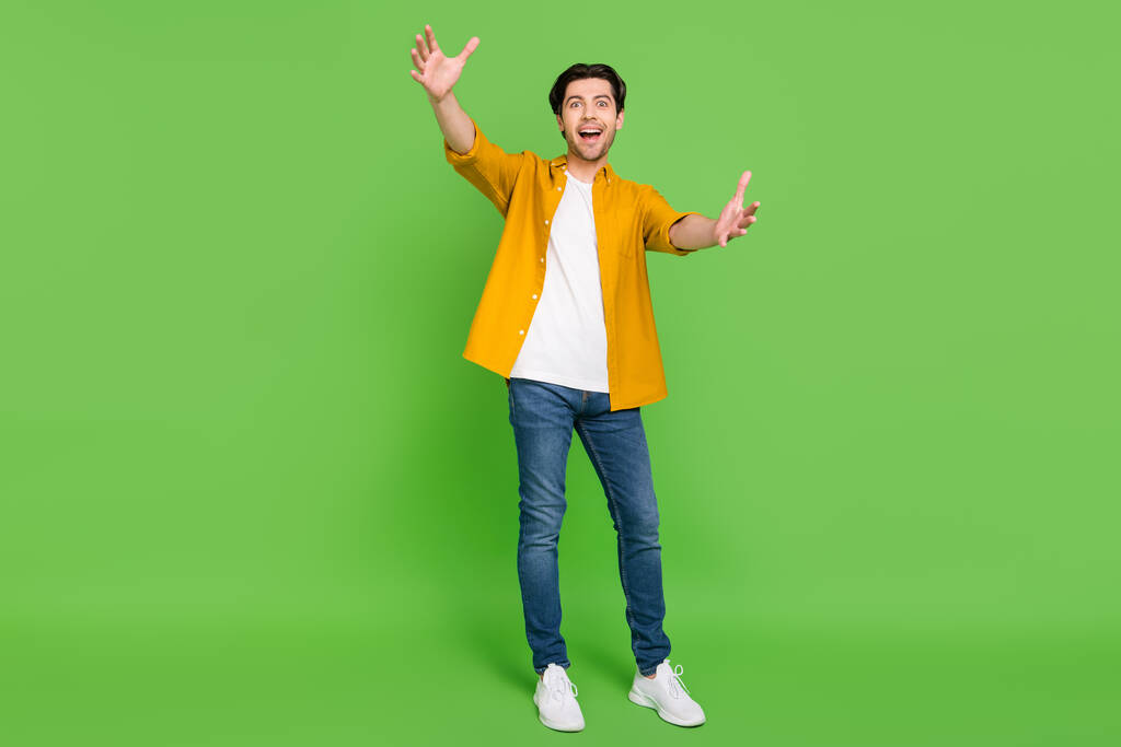Full size photo of young good looking excited crazy guy open hands meet friend hug embrace isolated on green color background - Photo, Image