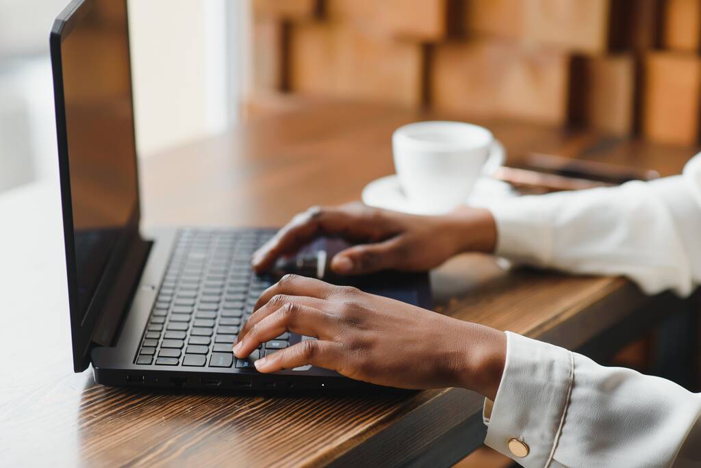 Imagen recortada de chica afroamericana bebiendo café mientras trabaja con una computadora portátil en la cafetería
 - Foto, imagen
