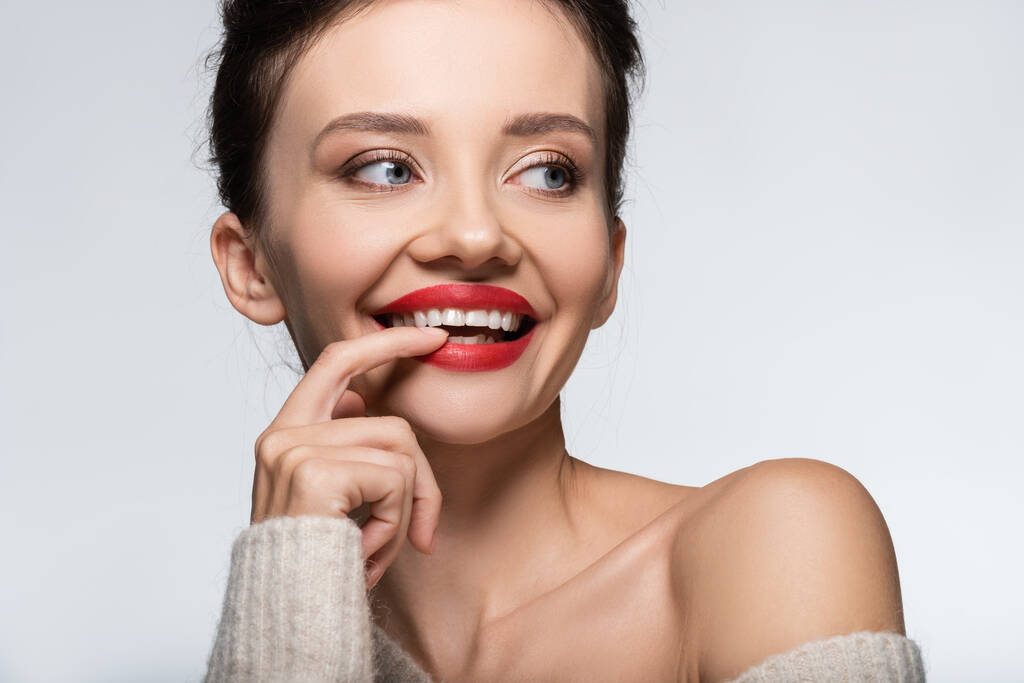 Pozitivní model ve svetru drží prst blízko zubů izolovaných na bílém - Fotografie, Obrázek