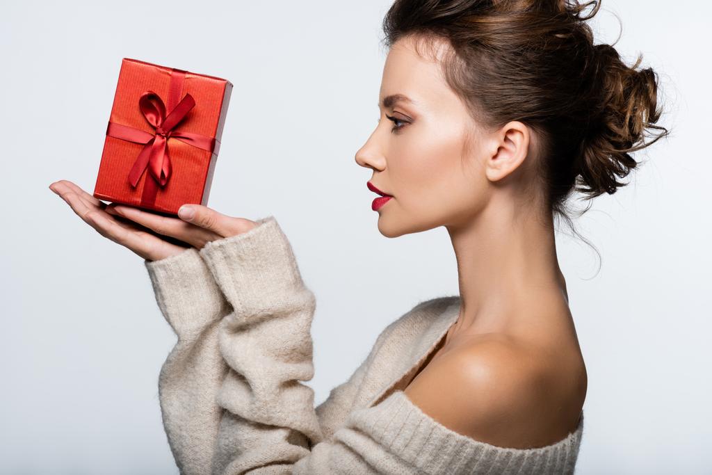 側ビューのスタイリッシュなブルネット女性見ます上の赤プレゼント孤立した上に白 - 写真・画像