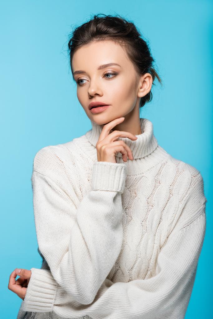 Hübsches junges Model in weißem Strickpullover auf blauem Grund - Foto, Bild