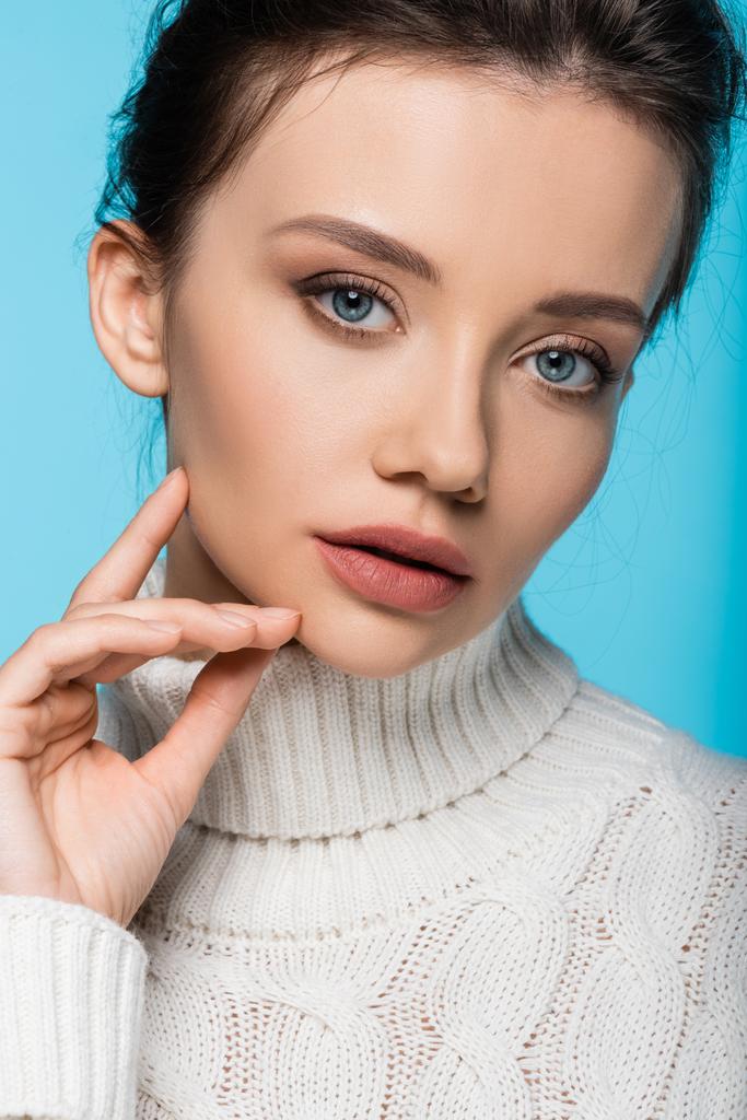 Portrait of model in knitted sweater looking at camera isolated on blue - Photo, Image