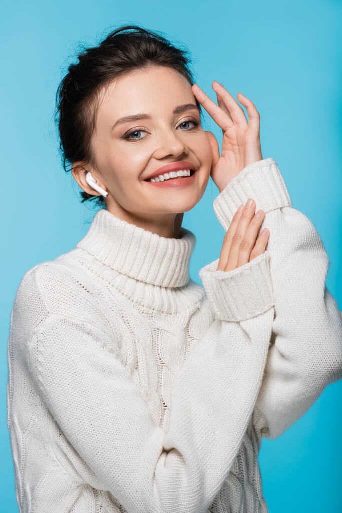 Positive woman in sweater and earphone posing isolated on blue - Photo, Image