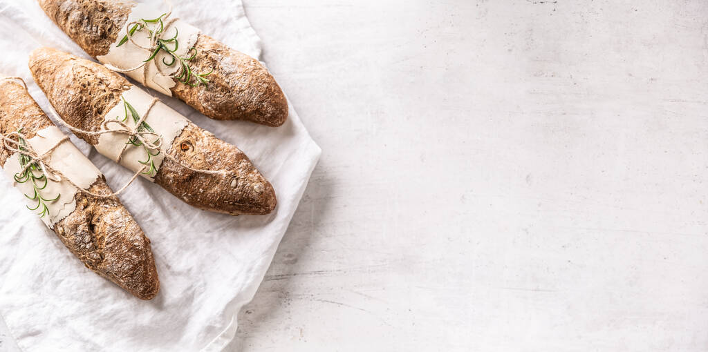Draufsicht auf frisches Brot auf einem weißen Leinentuch auf einem Drittel des Bildes. - Foto, Bild