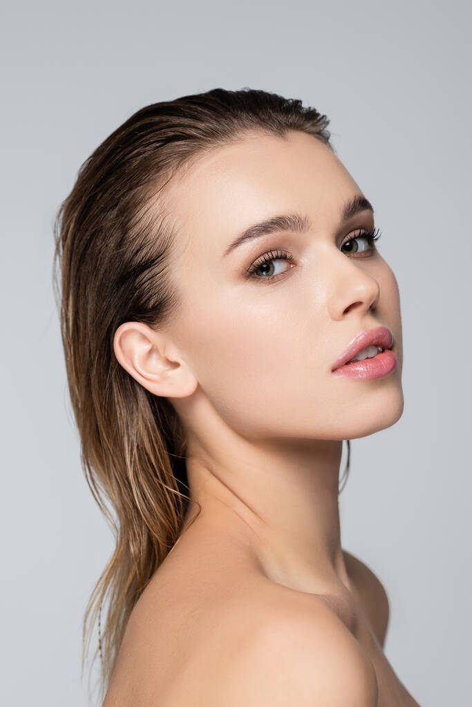 young woman with clean skin and natural makeup looking at camera isolated on grey - Photo, Image