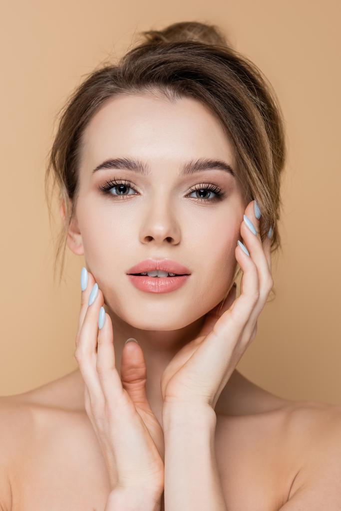 pretty woman with clean skin and natural makeup touching face isolated on beige - Photo, Image