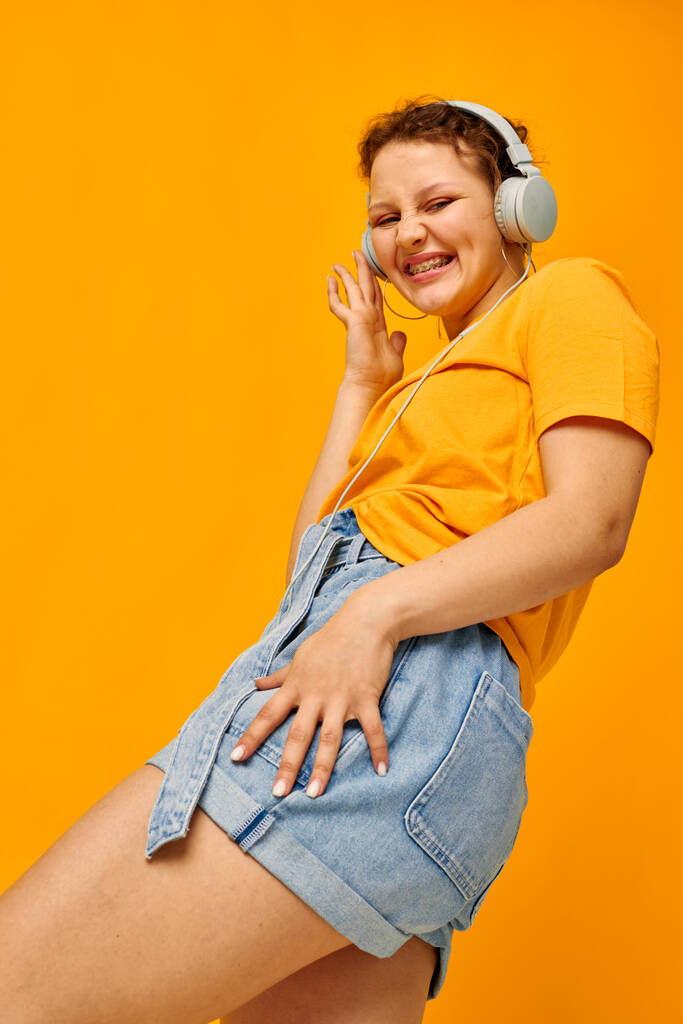 veselá žena žluté tričko sluchátka zábava hudba zábava žluté pozadí beze změny - Fotografie, Obrázek