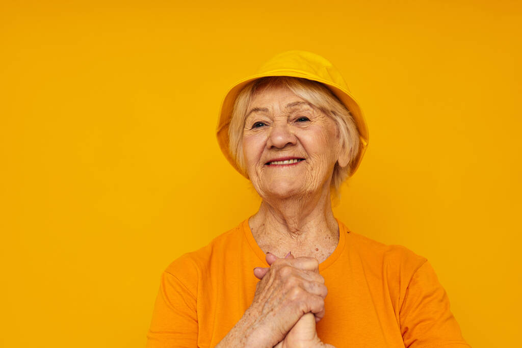 Lächelnde ältere Frau in lässigem T-Shirt mit gelbem Panamaausschnitt - Foto, Bild