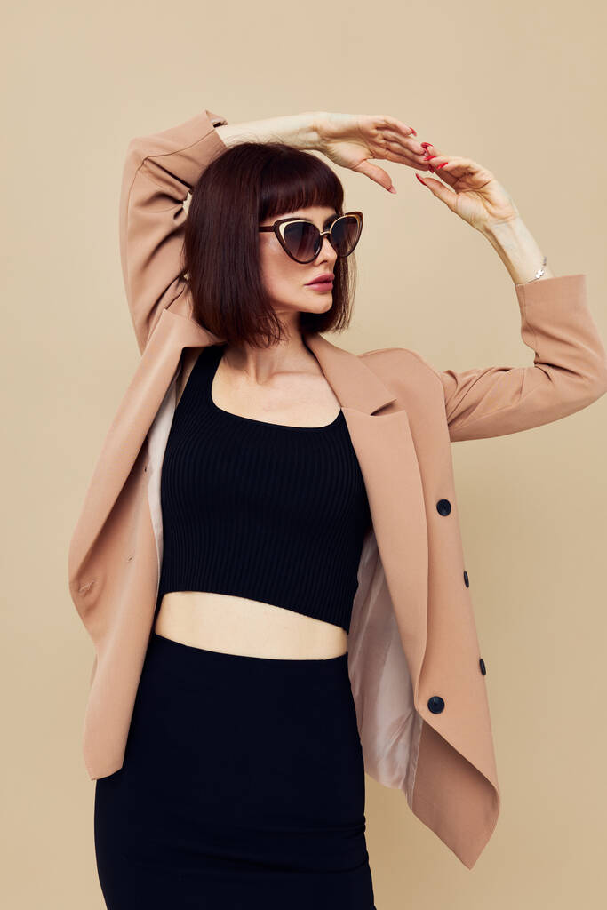 привлекательная женщина в бежевой куртке элегантный стиль солнцезащитные очки изолированный фон - Фото, изображение