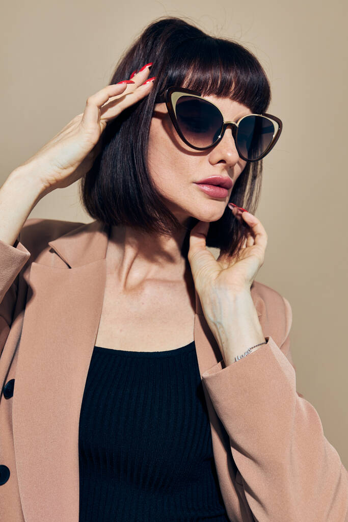 φωτογραφία όμορφη γυναίκα σε ένα μπεζ σακάκι κομψό στυλ γυαλιά ηλίου Lifestyle αμετάβλητη - Φωτογραφία, εικόνα