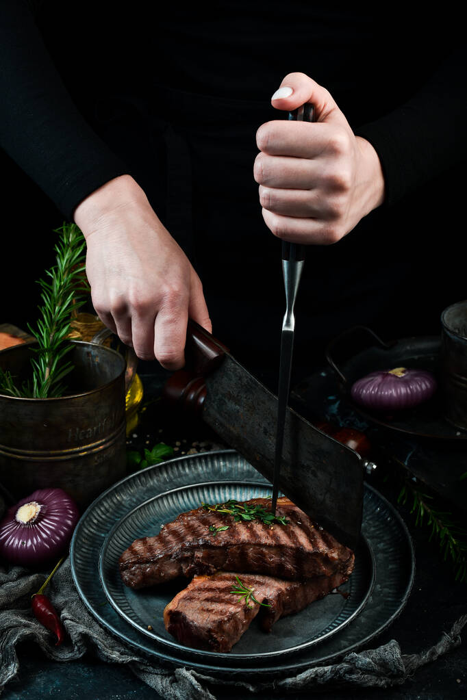 Šéfkuchař krájí grilovaný steak. Na černém kamenném pozadí. - Fotografie, Obrázek