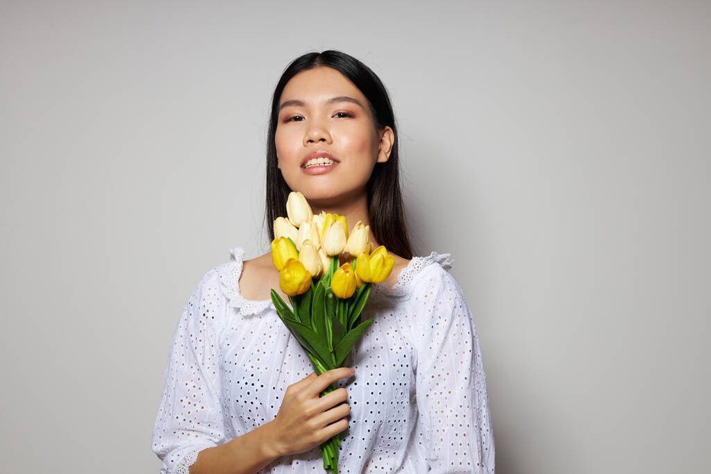 Retrato Asiático bela jovem mulher romance buquê de flores perto do rosto luz fundo inalterado - Foto, Imagem