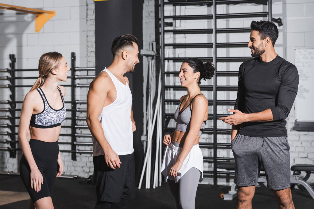 Pozytywne międzyrasowych przyjaciół w odzieży sportowej rozmowy w siłowni  - Zdjęcie, obraz