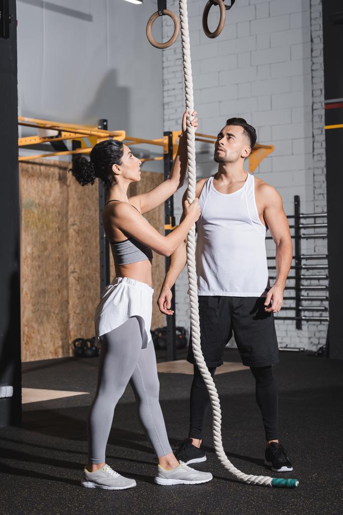 Interracial people in sportswear standing near climbing rope in sports center  - Photo, Image