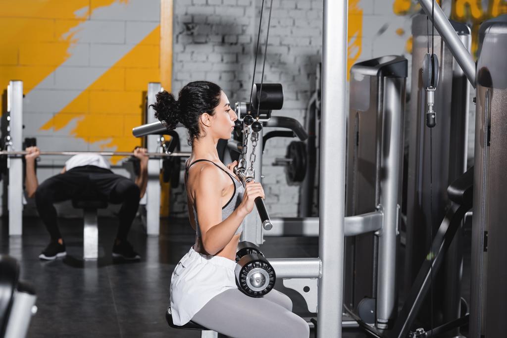 Moyen-Orient femme avec haltère formation sur lat machine de traction dans la salle de gym  - Photo, image