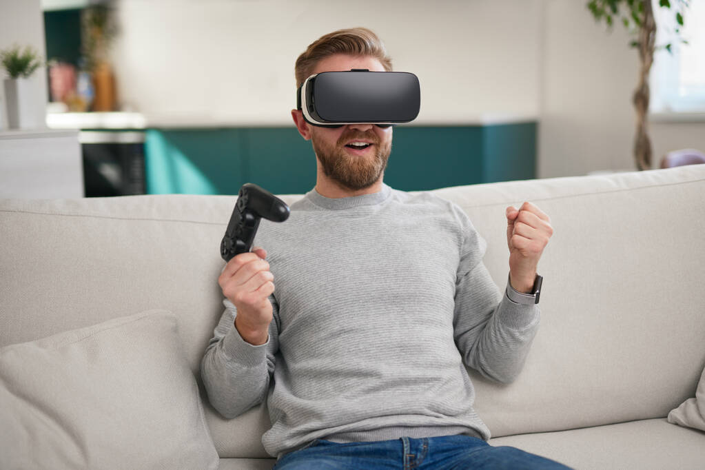 Щасливий чоловік у VR окулярах святкує перемогу в грі
 - Фото, зображення