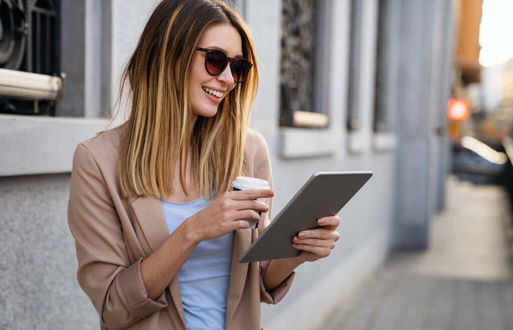 Porträt einer erfolgreichen jungen Frau mit digitalem Tablet während einer kurzen Pause im urbanen Hintergrund - Foto, Bild