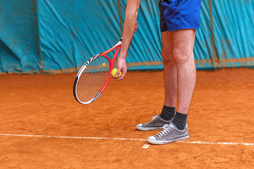 Jogador de tênis segurando raquete e bola amarela pronto para servir na quadra de tênis - Foto, Imagem