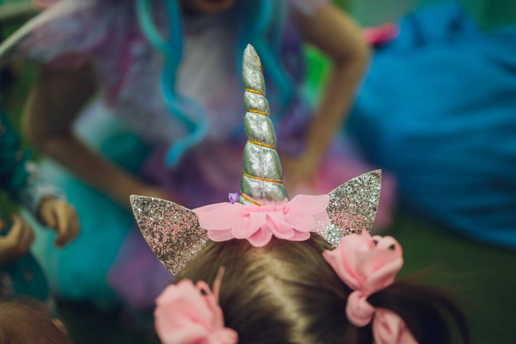 menina vestindo unicórnio headband com fundo rosa. Retrato de criança sorridente bonito com chifre de unicórnio e orelhas na frente brilhante parede rosa. Crianças encantadoras em trajes. - Foto, Imagem