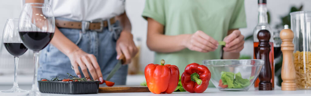 обрезанный вид лесбийской пары кулинарный салат возле бокалов красного вина на кухне, баннер - Фото, изображение