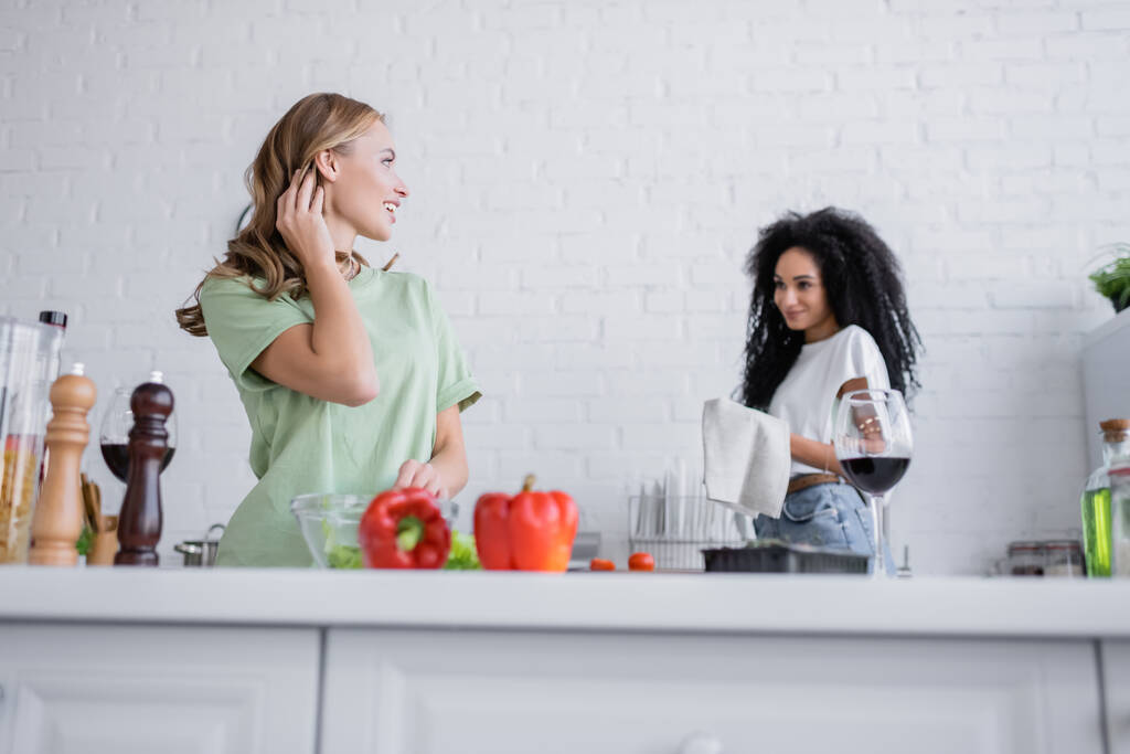 donna bionda guardando compiaciuta ragazza afro-americana in cucina - Foto, immagini