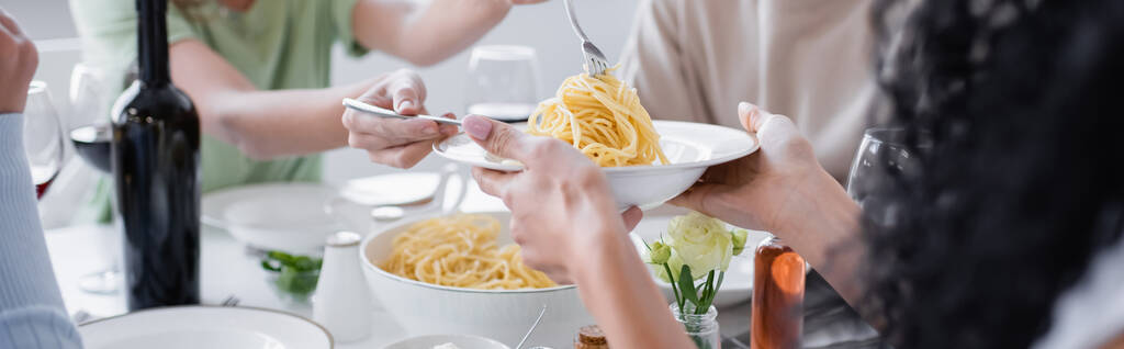 bijgesneden weergave van de vrouw die pasta aan wazig vriend, banner - Foto, afbeelding