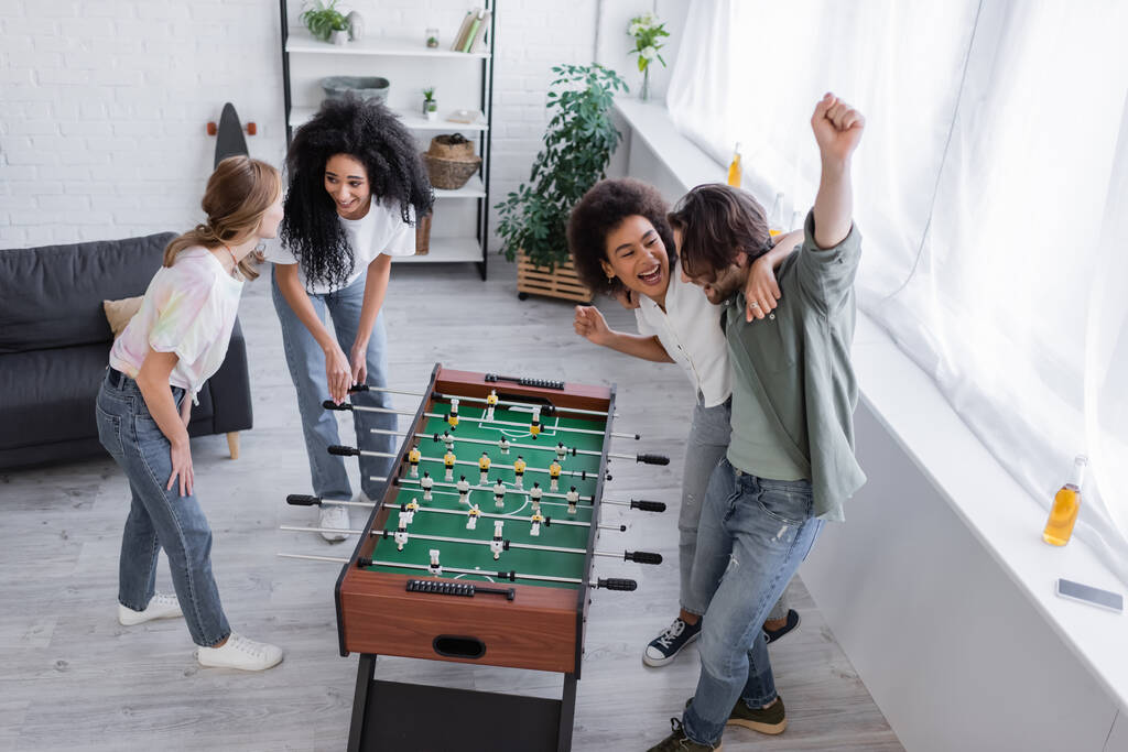 высокий угол зрения счастливых межрасовых друзей, радующихся за столом футбола  - Фото, изображение