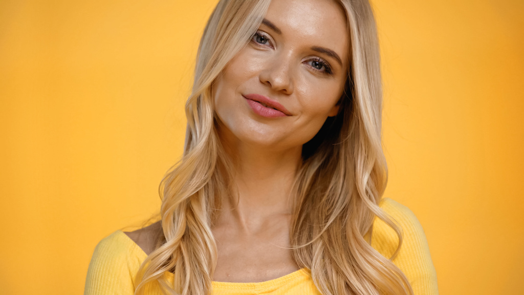 Sarı üzerine izole edilmiş kameraya bakan gülümseyen sarışın kadın portresi.  - Fotoğraf, Görsel