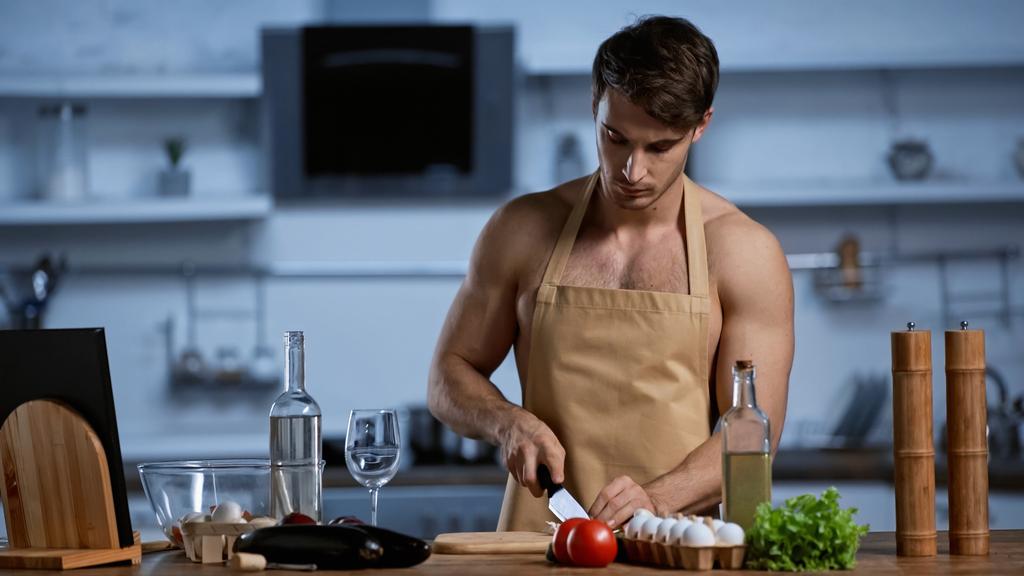 félmeztelen férfi kötényben főzés a modern konyhában - Fotó, kép