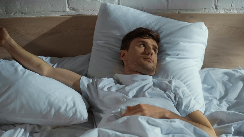 чоловік дивиться геть, лежачи на ліжку на безсонну ніч
 - Фото, зображення