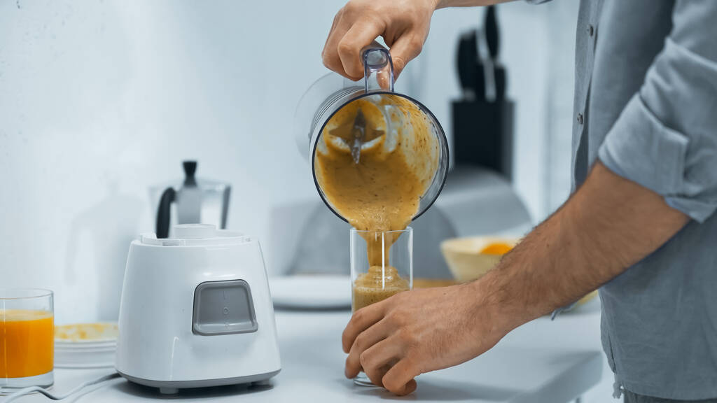 levágott kilátás az ember öntés friss smoothie üvegbe a konyhában - Fotó, kép