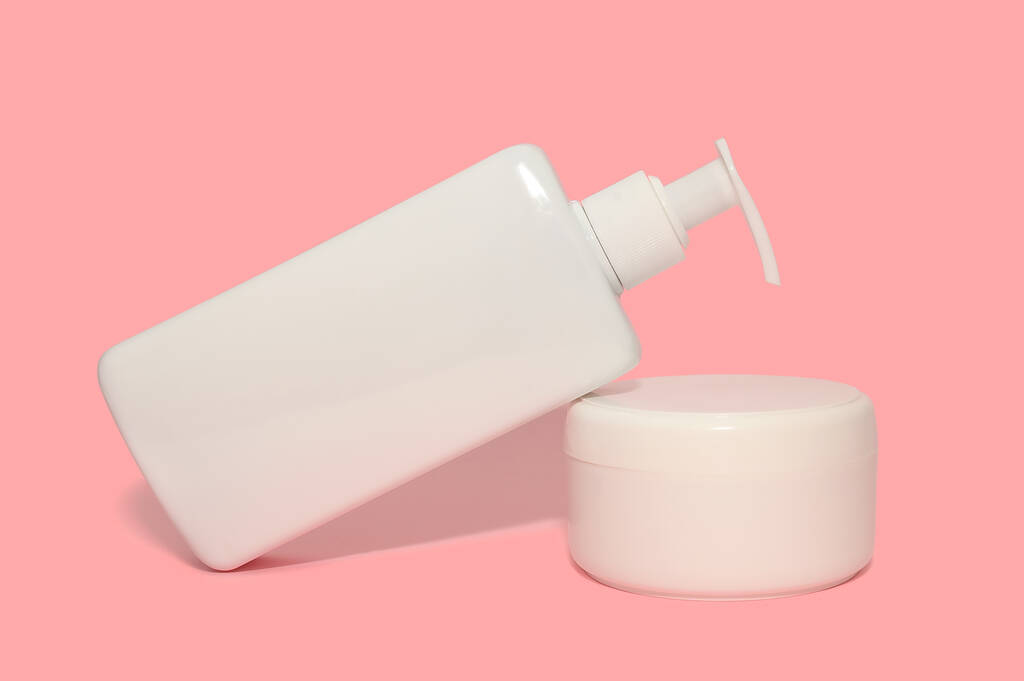 Crème en hydraterende lotion in een witte body container. Op een roze achtergrond. - Foto, afbeelding