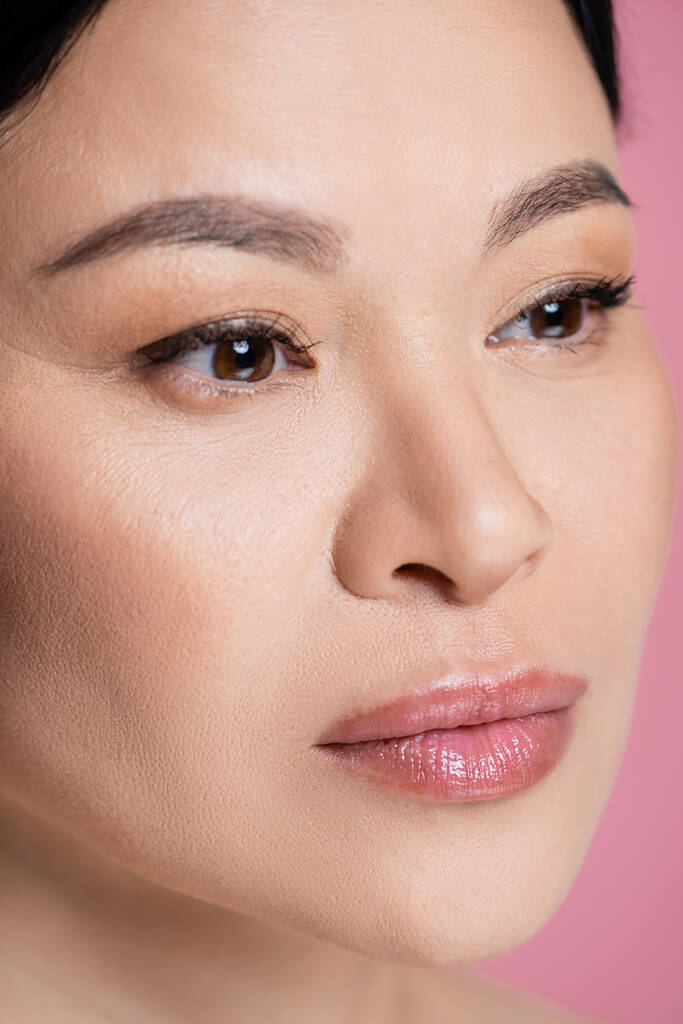 Nahaufnahme der asiatischen Frau mit Make-up isoliert auf rosa  - Foto, Bild