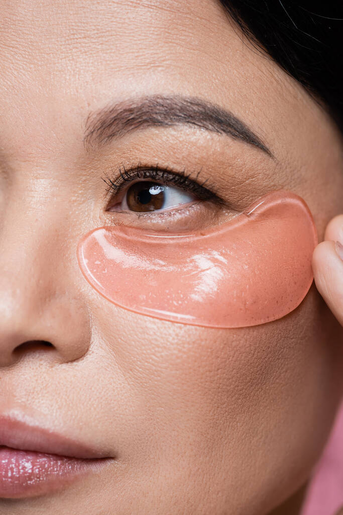 ピンクの上に隔離された目のパッチを適用アジアの女性のクローズアップビュー  - 写真・画像