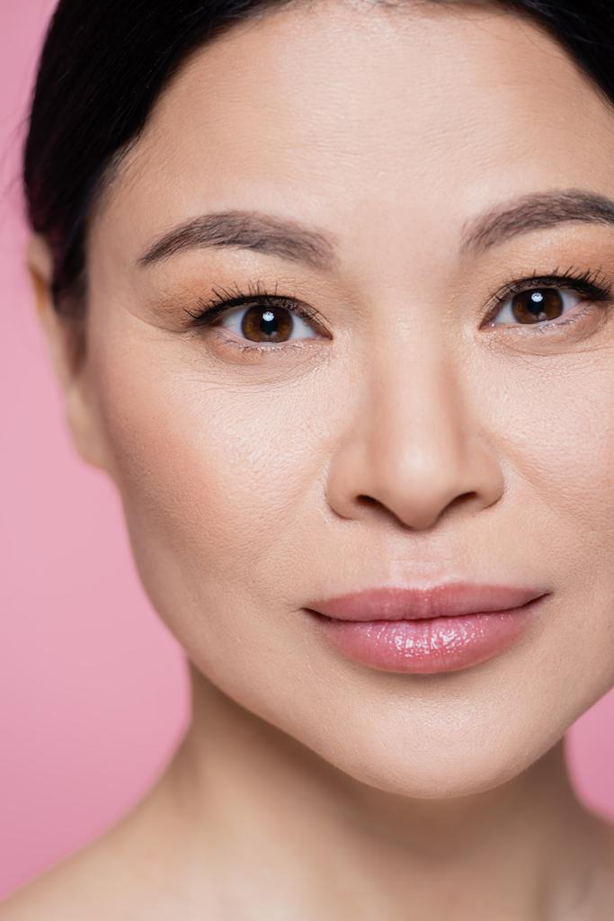 close-up uitzicht van aziatische vrouw met gezicht kijken naar camera geïsoleerd op roze  - Foto, afbeelding