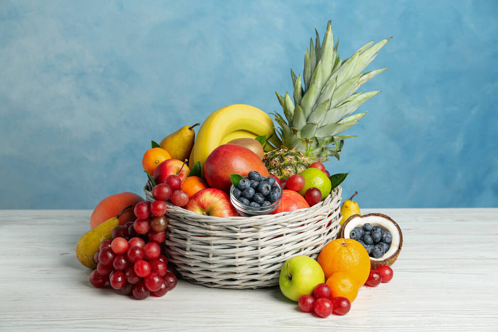 Surtido de frutas exóticas frescas sobre mesa de madera blanca sobre fondo azul claro - Foto, Imagen