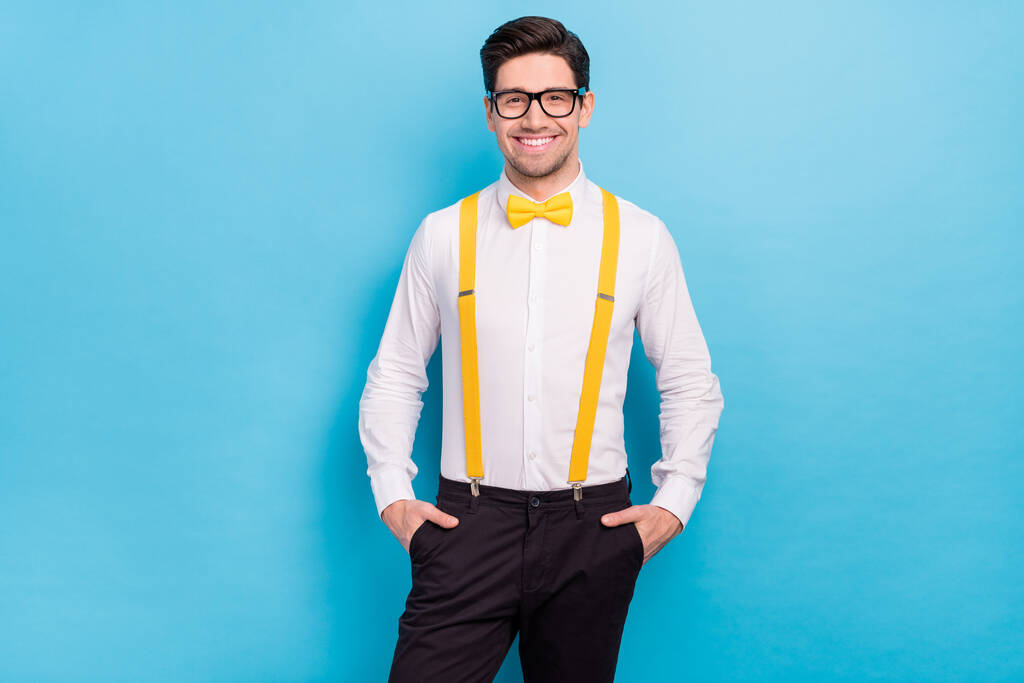 Photo of charming funky guy dressed white shirt yellow bowtie glasses hands arms pockets isolated blue color background - Photo, Image