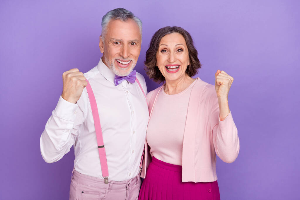 Foto de socios encantados emocionados levantan el triunfo de los puños aislados en el fondo de color violeta - Foto, imagen