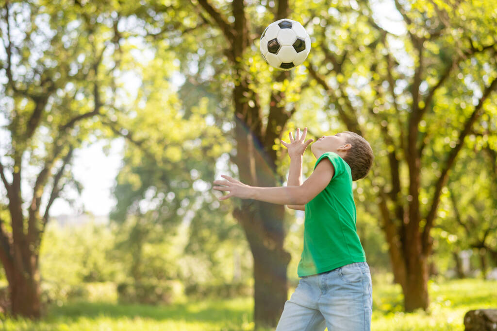 Boy sideways to camera tossing up ball - Photo, Image