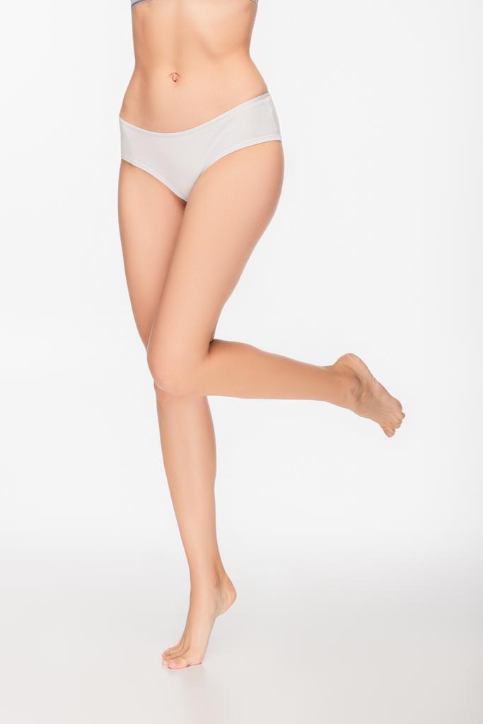 częściowy widok boso kobieta w majtki stojące na jednej nodze na białym tle - Zdjęcie, obraz
