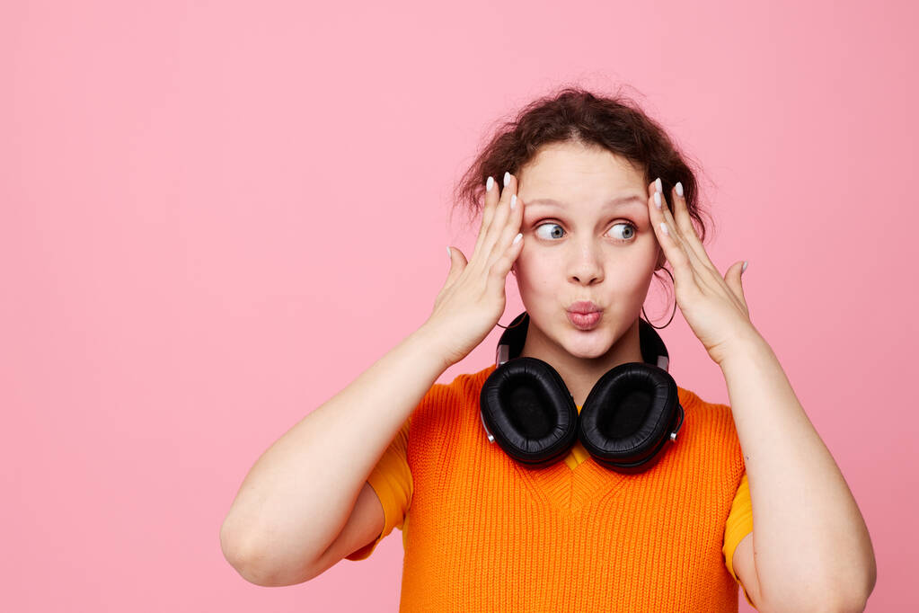 portrait d'une jeune femme dans un pull orange écouteurs musique divertissement vue recadrée inchangée - Photo, image