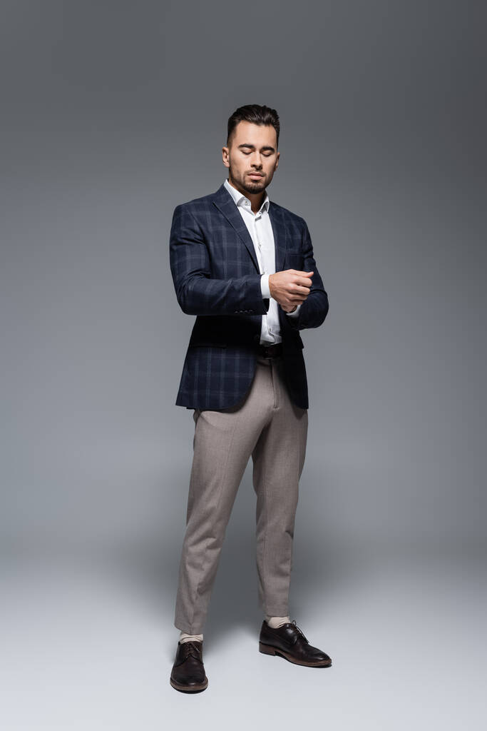 in voller Länge junger bärtiger Geschäftsmann im Anzug steht auf grau - Foto, Bild