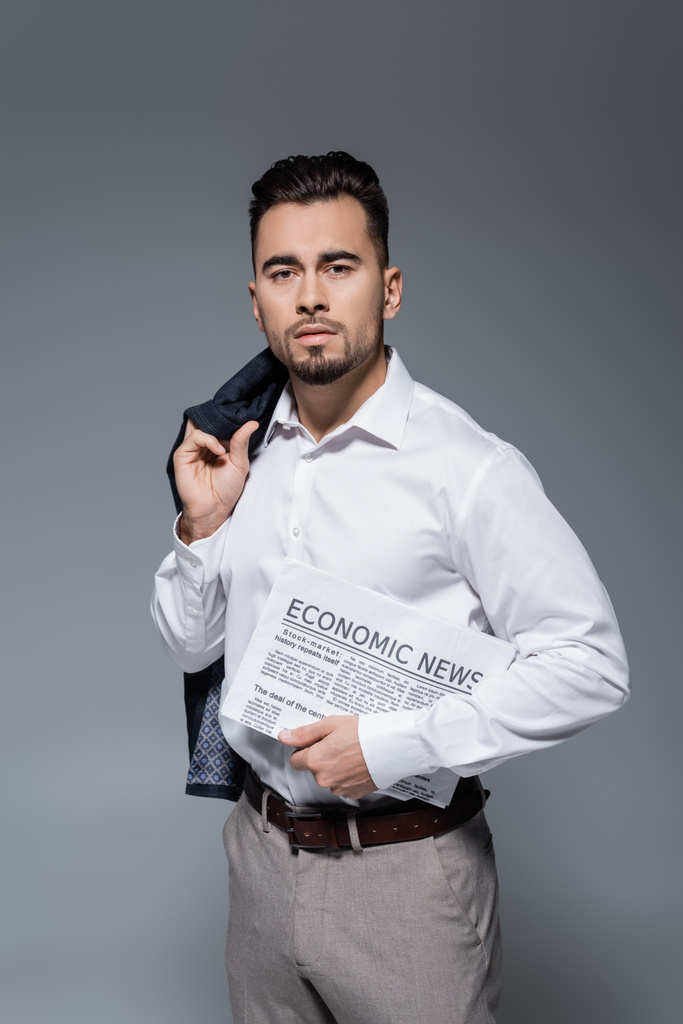 giovane uomo d'affari barbuto in giacca e cravatta con giornale isolato su grigio - Foto, immagini